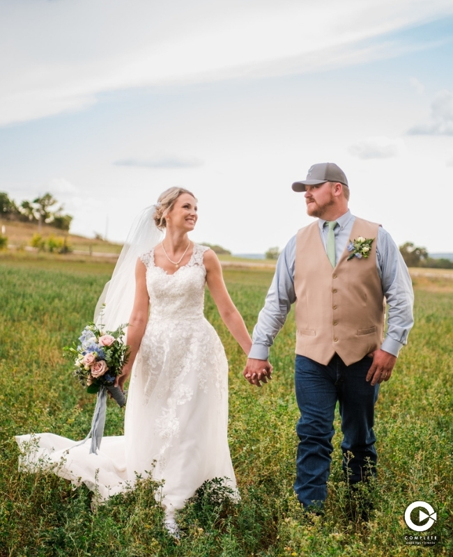 Bride and groom holding hands looking at each other. 